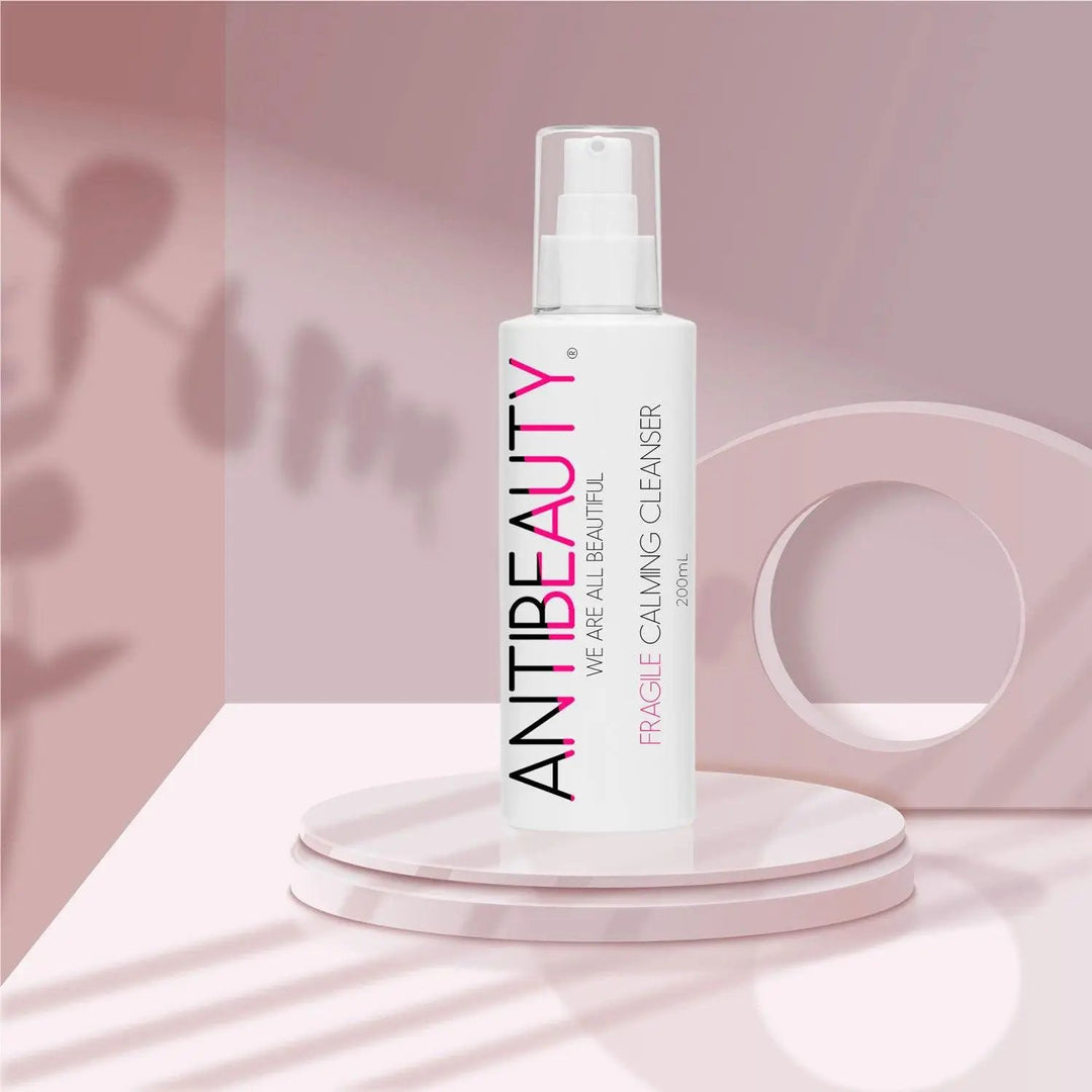 AntiBeauty Fragile Calming Cleanser - a gentle and effective solution for delicate skin - on a pastel pink platform background.