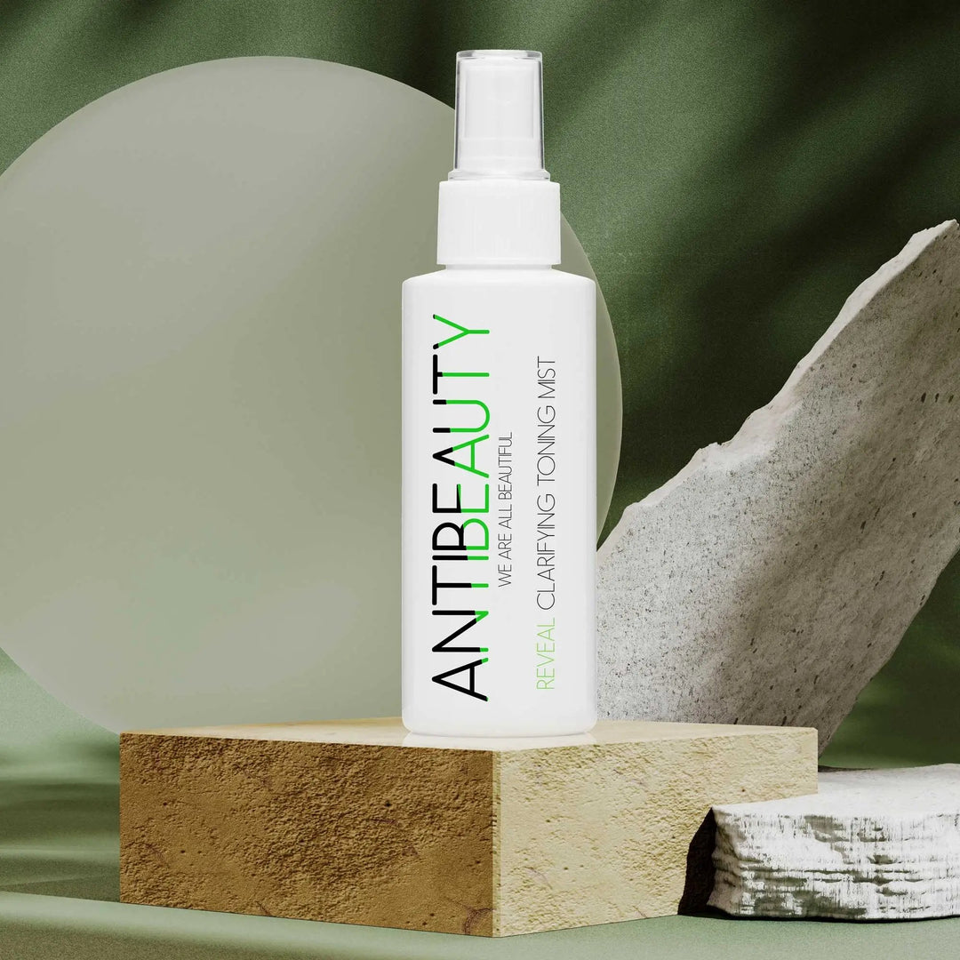 Reveal Clarifying Toning Mist on stone platform in front of a green and rock background