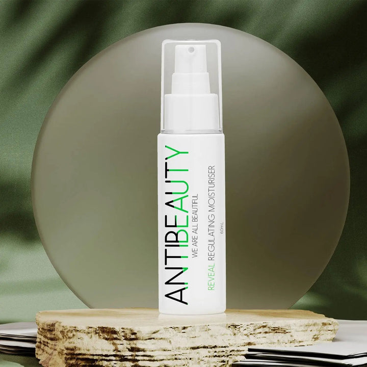 AntiBeauty Reveal Regulating Moisturiser - a gentle and effective solution for oily and acne prone skin - on a stone platform in front of a green background.