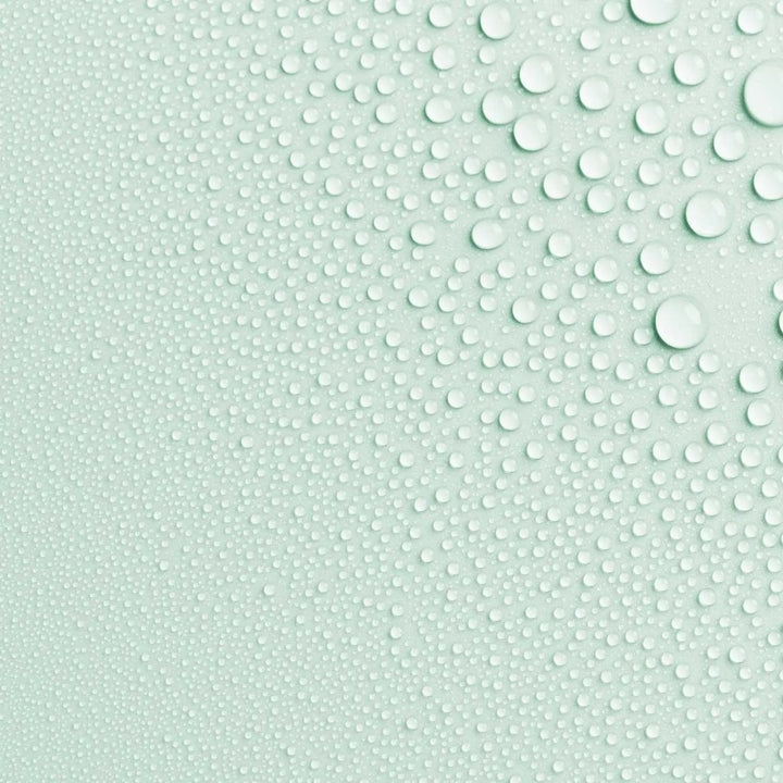 Close-up photo of AntiBeauty Reveal Clarifying Toning Mist texture, with fine mist droplets on a mint coloured background.